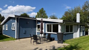 Sininen talo, jossa on patio, ulkotila istumiseen ja savupiippu.