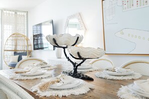 A dining table with white plates, a decorative tree sculpture, and woven placemats.