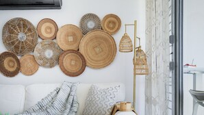 A modern living room with a white sofa, a coffee table with books and a plant, a wall decorated with woven baskets, and a floor lamp. - Front beach Charming apartments 2-bedroom apartment  in Cabo Rojo (Cabo Rojo)