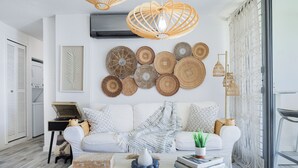 A modern living room with a white sofa, decorative wall art, and a coffee table with books and a vase. - Front beach Charming apartments 2-bedroom apartment  in Cabo Rojo (Cabo Rojo)