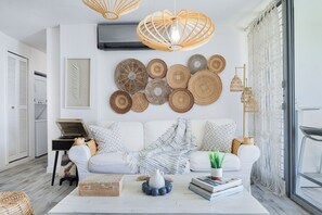 A modern living room with a white sofa, decorative wall art, and a coffee table with books and a vase.