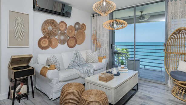 A modern living room with a white sofa, a coffee table, wicker chairs, and a large window with a view of the sea. - Front beach Charming apartments 2-bedroom apartment  in Cabo Rojo (Cabo Rojo)