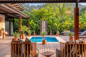 A poolside area with wooden deck seating and potted plants. - Villa Yakole– Spacious Tropical Retreat (Puerto Viejo)