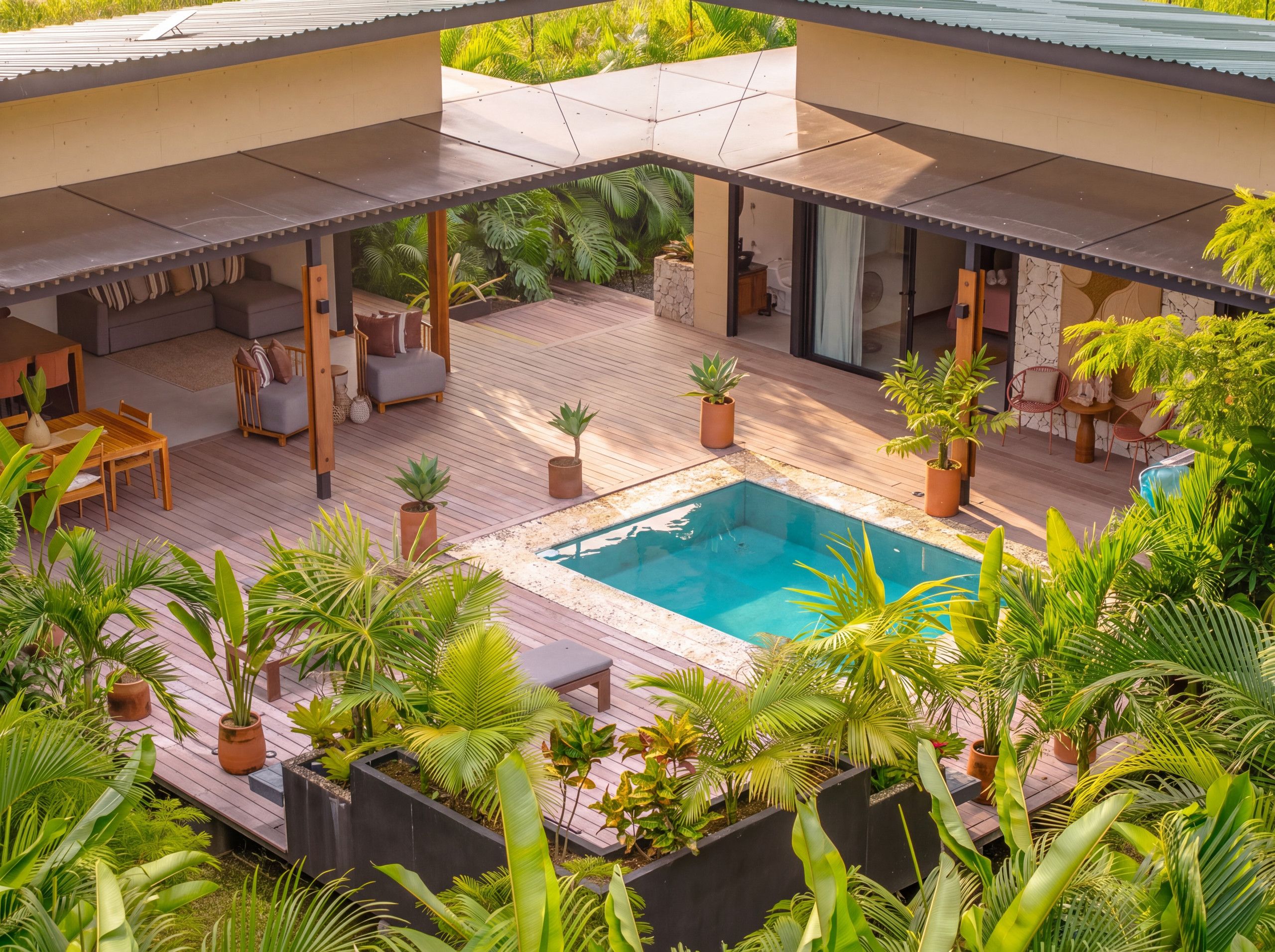 A poolside area with a wooden deck, lounge seating, and potted plants.