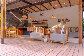 A modern living room with a wooden floor, two sofas, a dining area with a table and chairs, and a kitchen in the background. - Villa Yakole– Spacious Tropical Retreat (Puerto Viejo)