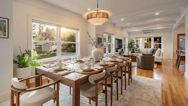 A spacious dining area with a long wooden table set for a meal, surrounded by comfortable seating. - Phinney Ridge Luxe Retreat | Gym, BBQ & Game Room (Seattle)