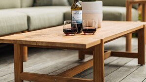 A wooden table with a bottle of wine and two glasses on a wooden deck. - Phinney Ridge Luxe Retreat | Gym, BBQ & Game Room (Seattle)