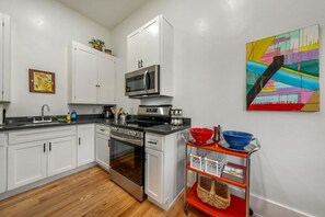 A modern kitchen with white cabinets, stainless steel appliances, and a red cart with baskets. - Historic Duplex / 1 BR 1 BA / Near 4th & Congress (Tucson)