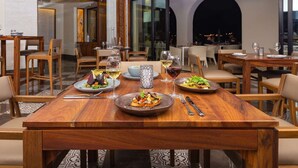 A restaurant with wooden tables and chairs, serving dishes with wine glasses. - Luxurious Oceanfront 5 STAR Resort Suite at Villa la Valencia with a Lazy River! (San José del Cabo)