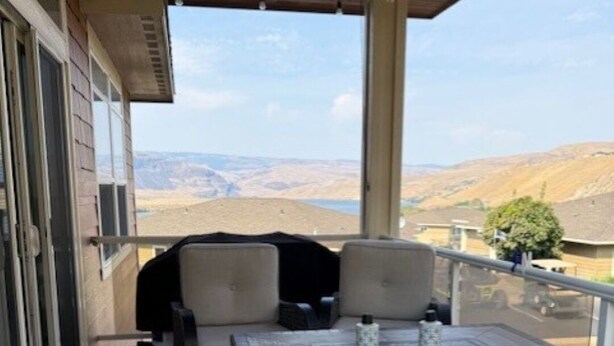 Un patio techado al aire libre con una mesa y sillas, con vistas a un paisaje montañoso.