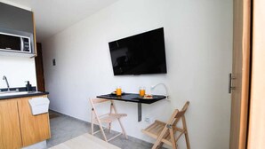 A compact kitchen with a microwave, a sink, and a small dining area with two chairs and a table. - Relajante estudio con espacio óptimo y balcón (Guadalajara)