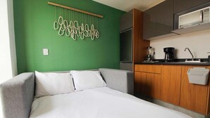 Ein kleines Zimmer mit Bett, einer Küchenzeile und einer Wand in Grünton.