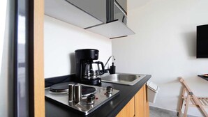 Eine moderne Küche mit Kaffeemaschine, Spüle und einem flachbildschirmfernseher an der Wand.