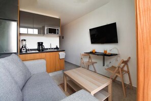 A compact living space with a kitchenette, a flat-screen TV, a sofa, and a small dining table. - Departamento nuevo en zona Americana (Guadalajara)