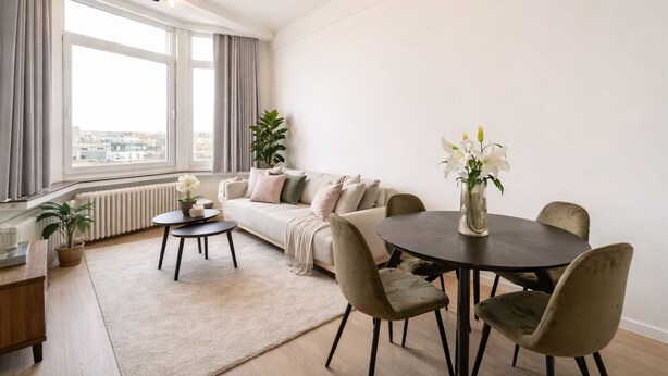 Una sala moderna con un sofá, una mesa de comedor redonda con sillas, una mesa de centro y una planta en maceta.