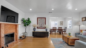 A modern living room with a fireplace, wooden flooring, a dining area, and a sofa. - Brilliant 5-bedroom single level house in charming Alhambra (Alhambra)