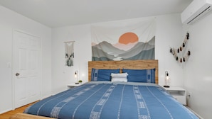A bedroom with a wooden headboard, a blue bedspread, a wall tapestry, and a bedside lamp. - Brilliant 5-bedroom single level house in charming Alhambra (Alhambra)