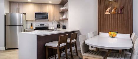 A modern kitchen with a central island, stainless steel appliances, and a dining area with a round table and chairs.