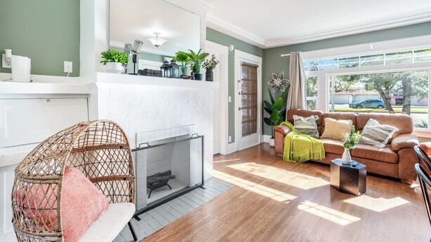 A living room with a fireplace, a sofa, a coffee table, and a large window with a view of the outside.