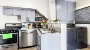 A compact kitchen with a stove, microwave, sink, and dishwasher.