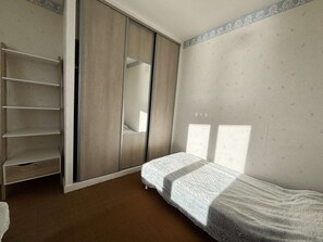 A bedroom with a bed, a wardrobe, and a shelf unit. - Unobstructed sea view – 2-room apartment in La Forêt-Fouesnant! (LA FORET FOUESNANT)