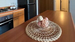 A modern kitchen with wooden cabinets, a stainless steel refrigerator, and a woven placemat on the countertop. - Brisa del Sol Apartment - Comfortable and well located (Talcahuano)