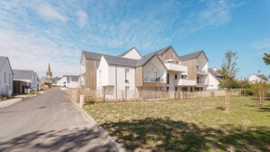 A residential street with modern houses, a clear sky, and a church spire in the distance. - Carnac – 2-bedroom apartment – 58 sqm - WIFI (CARNAC)