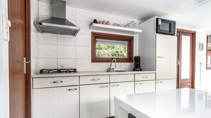 Una cocina moderna con armarios blancos, una campana extractora de acero inoxidable, una ventana con vistas y un microondas integrado.