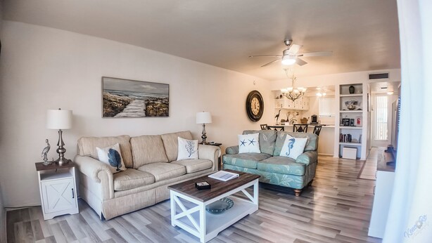 A living room with two sofas, a coffee table, a dining area, and a kitchen. - Steps Away from the Beach! Runaway Bay #202 (Bradenton Beach)