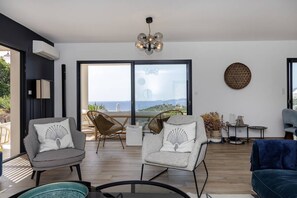 A modern living room with two armchairs, a sofa, a chandelier, and a large window with a view. - Villa LAETIZIA- 5 bedrooms, swimming pool, sea view (PIETROSELLA)