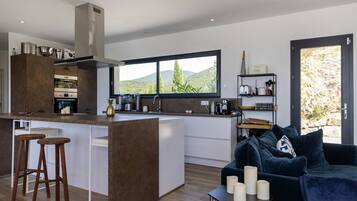 Une cuisine moderne dotée d’un îlot central, de tabourets de bar et offrant une vue sur l’extérieur.