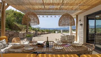 Un espace de restauration en plein air offrant une vue sur le paysage, avec des meubles en osier et une table dressée pour un repas.