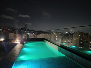 A rooftop pool with a cityscape view at night. - Charming and comfortable studio in Lapa | Perfect location | Pool and tranquility (Rio de Janeiro)