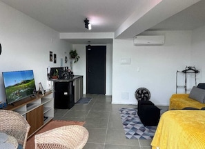 A modern living room with a television, sofa, and a dining area. - Charming and comfortable studio in Lapa | Perfect location | Pool and tranquility (Rio de Janeiro)