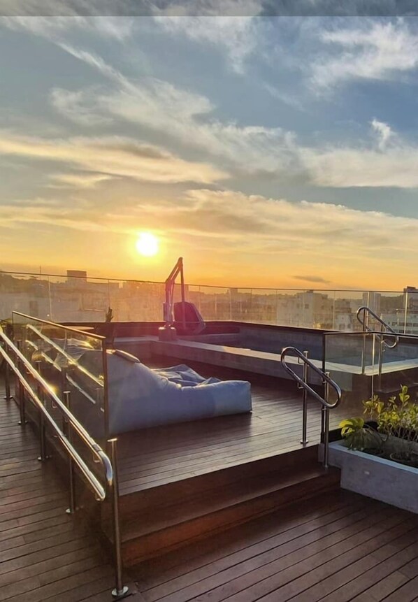 A rooftop terrace with a sunlit view, a lounge area with a white sofa, and a small garden. - Charming and comfortable studio in Lapa | Perfect location | Pool and tranquility (Rio de Janeiro)