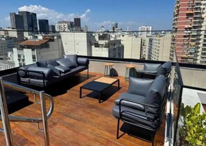 A rooftop terrace with leather sofas, a coffee table, and a small round table. - Charming and comfortable studio in Lapa | Perfect location | Pool and tranquility (Rio de Janeiro)
