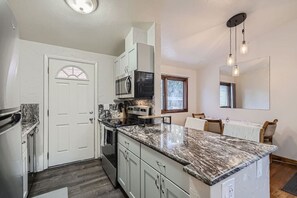 A kitchen with white cabinets, a granite countertop, a microwave, and a window. - Cozy Arvada Home | Pets OK + Workstation + Yard (Arvada)