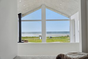 Ein Zimmer mit großem Fenster und Meerblick sowie einer Grünfläche.