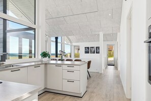 Eine moderne Küche mit einer großen Kochinsel, weißen Schränken und Meerblick.
