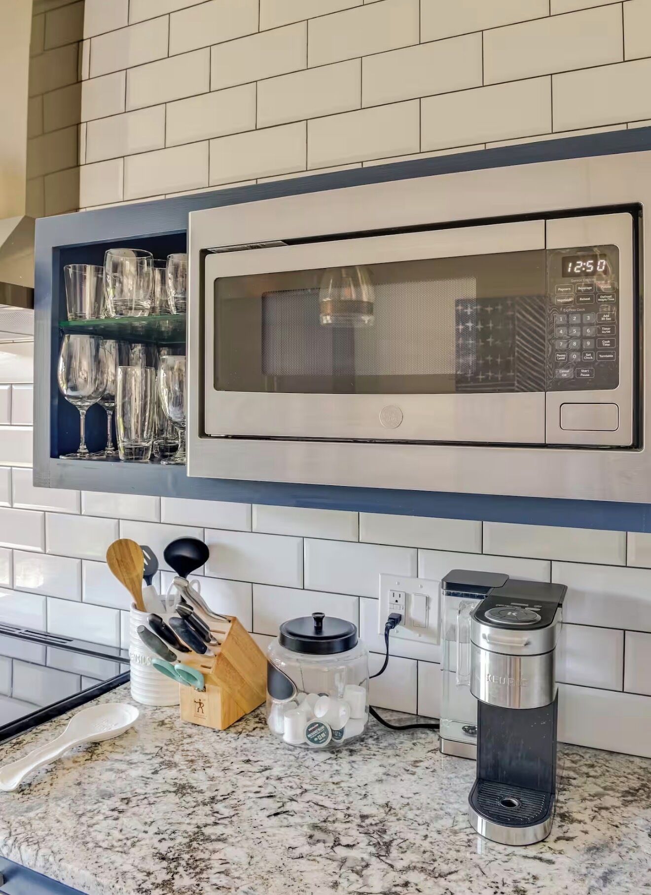A kitchen with a microwave, a coffee maker, and a spice rack.