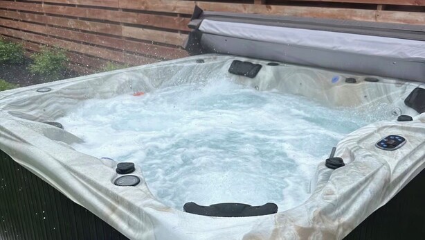 Ein Whirlpool mit Holzterrasse und Metallrahmen.