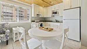A modern kitchen with white cabinets, a round dining table, and a wooden ceiling. - Sunset and Sunrise - With Pool next to Beach! (St. Pete Beach)