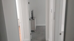A narrow hallway with white walls and carpeted flooring.