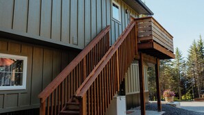 A wooden staircase leading to a balcony attached to a building with vertical siding. - In-Town Homer Hideaway 3BR/2BA (Homer)
