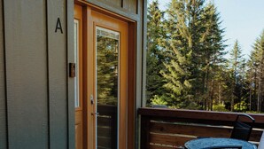 A wooden deck with a door, a bench, and a table with chairs. - In-Town Homer Hideaway 3BR/2BA (Homer)