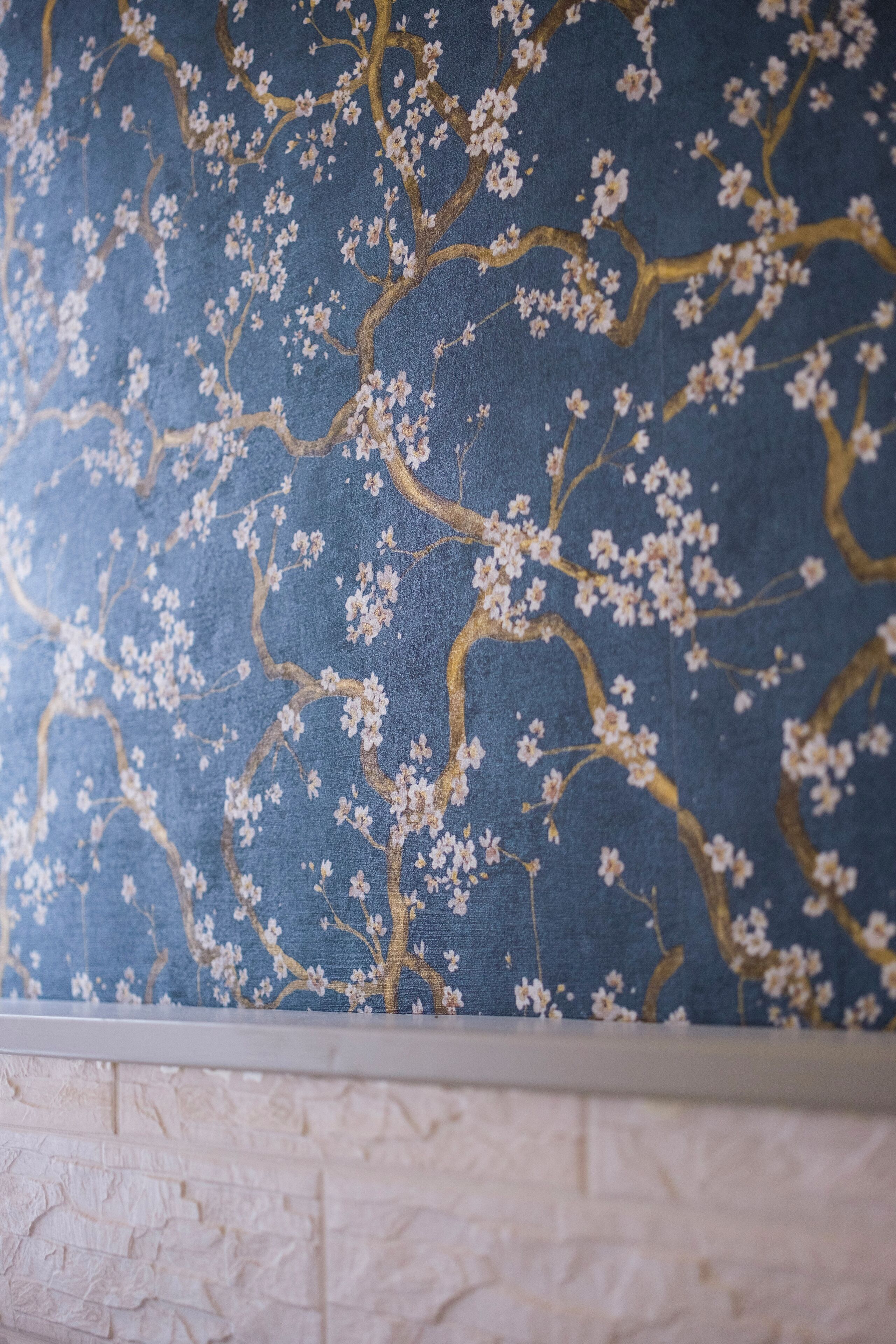A wall with a floral pattern and a textured white baseboard.