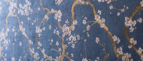 A wall with a floral pattern and a textured white baseboard.