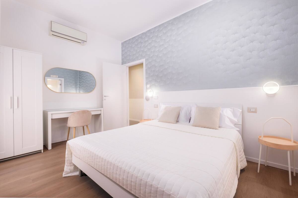 Une chambre à coucher comprenant un lit, un bureau, une chaise, une armoire et un miroir.