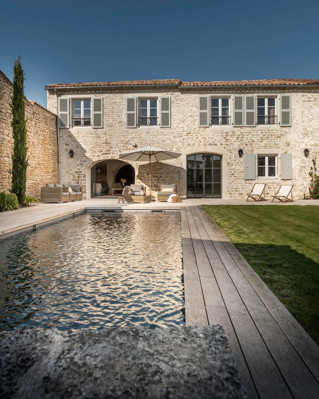Un bâtiment en pierre doté d’une piscine, d’un espace extérieur aménagé et d’une terrasse en bois.