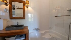 Un bagno moderno con un mobile vanitario in legno, uno specchio grande, una vasca da bagno e un box doccia in vetro.
